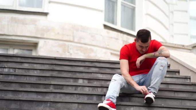 年轻的男性在大学的台阶上打扫鞋子。男子学生在教育机构的楼梯上订购运动鞋