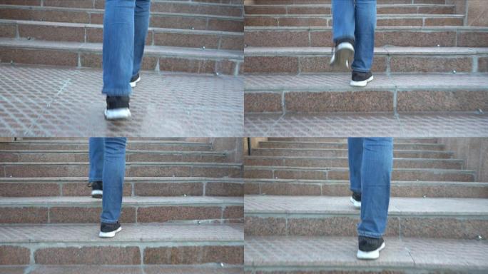 穿着牛仔裤的女人的脚爬楼梯。走上楼梯。低角度视图。穿着靴子和牛仔裤的女人的腿，向上。在城市里散步。城