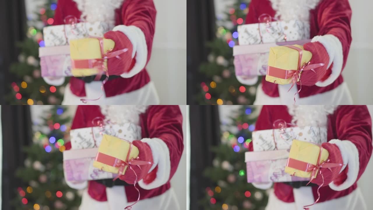 穿着圣诞老人服装的面目全非的男人在新年树前送礼物。拿着礼品盒的人。节日快乐、传统、圣诞节的概念