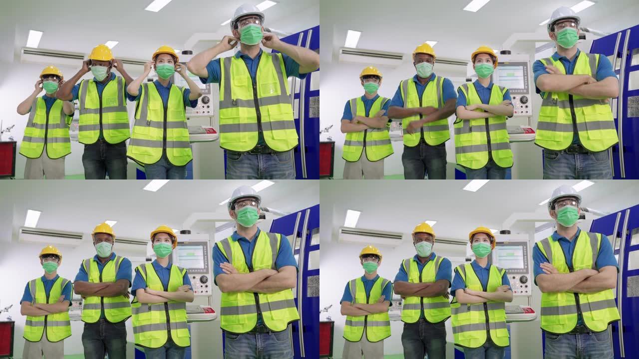 多民族工程师站立双臂交叉，戴着外科口罩，以防止制造工厂新型冠状病毒肺炎。工作场所种族平等的概念。
