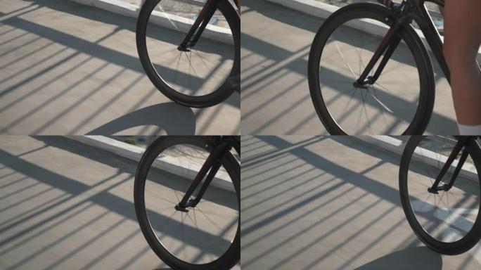 日落灯光下自行车车轮的轮廓。女孩正在骑自行车，自行车装备的特写镜头。骑自行车的人在日出时踩着自行车。