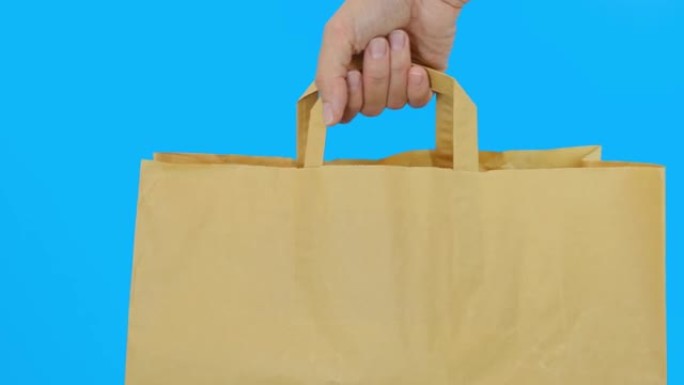 蓝色背景下的手提纸袋，使用可回收的袋子进行购买，以节省自然，环保