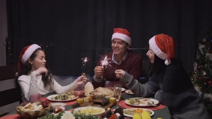 快乐的家庭聚会和玩火花火在餐厅庆祝圣诞晚餐