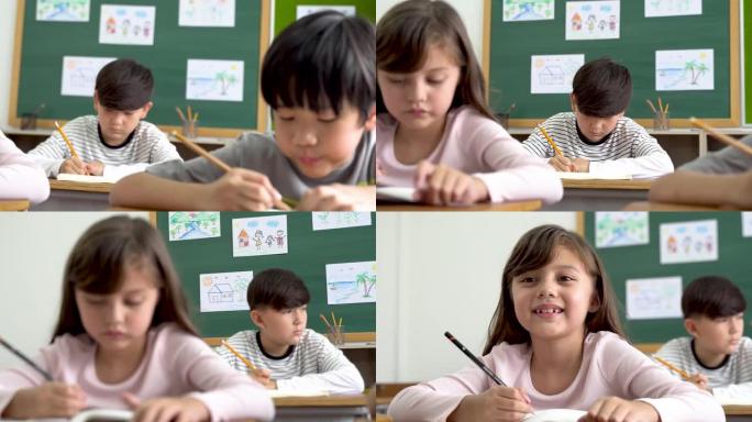 快乐的女学生坐在教室的桌子上微笑的肖像。可爱的高加索小学女孩坐在学校在纸上写字，看着相机，教育，学习