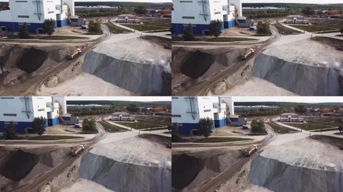 采石场在工作时间的空中俯视图。库存镜头。工业背景采砂场和一辆装载的卡车开到工厂，专业设备和机械