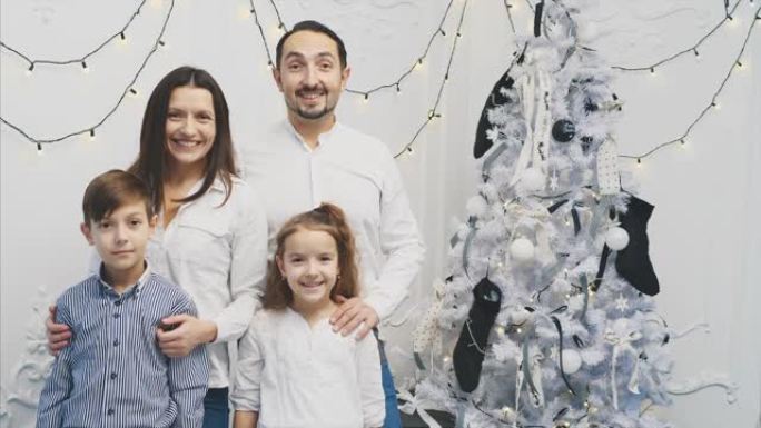 幸福的家庭成员: 圣诞树附近白色背景上的母亲，父亲，儿子，女儿。