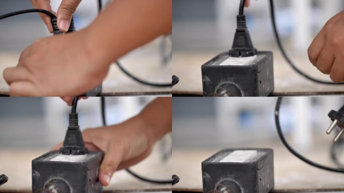 一名妇女的特写手拉动插入插座的电线，以节省慢动作的能量