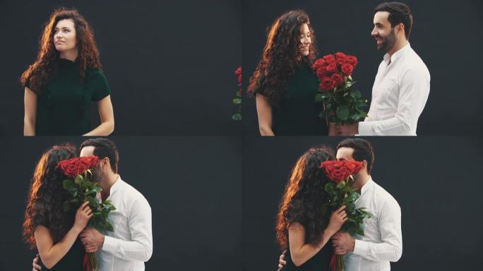 浪漫的年轻人给女友一束红玫瑰。他们躲在花后面接吻。