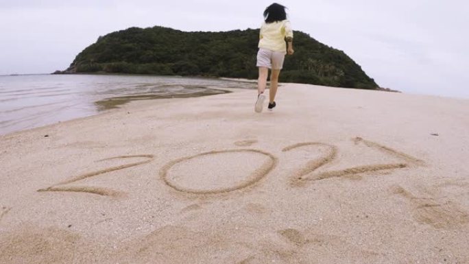 特写亚洲女人跳过2021新年，在沙滩上奔跑，手臂在海滩和岛屿上举起