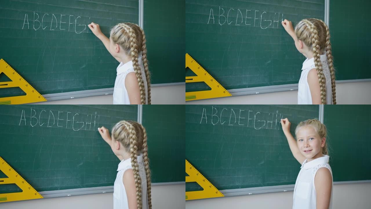 黑板上快乐的女学生的肖像在教室里用白色粉笔写字，看着相机，小学英语课