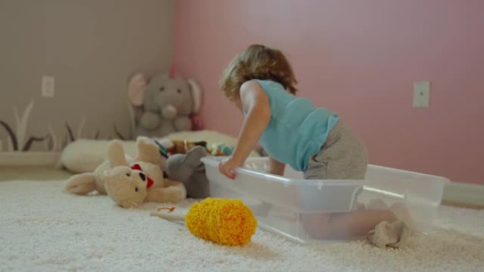 小女孩的慢动作进入带有玩具的塑料垃圾箱