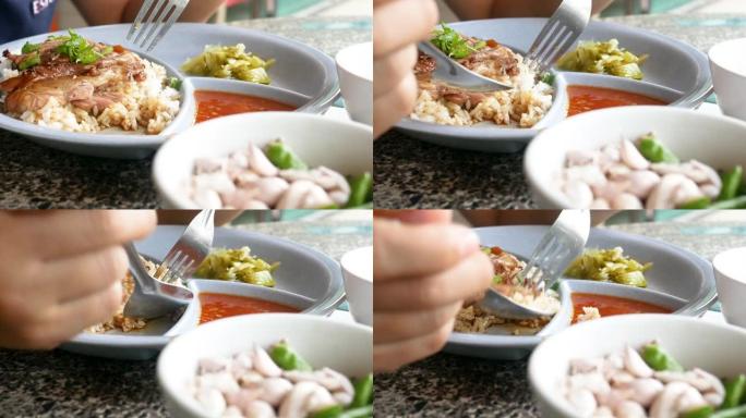 女人的手用勺子和叉子特写，用甜肉汁酱炖猪腿放在盘子里。美味的泰国菜。