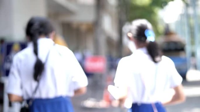 快乐的亚洲女学生早上戴着口罩，然后带着阳光上学。