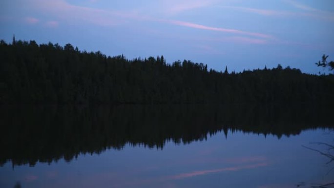 阴暗的森林在反光的湖中，五颜六色的天空
