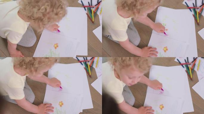 一个小女孩的手和头的特写，她正在用铅笔在地板上的白纸上画画。向父亲抬起头。铅笔，纸在她面前
