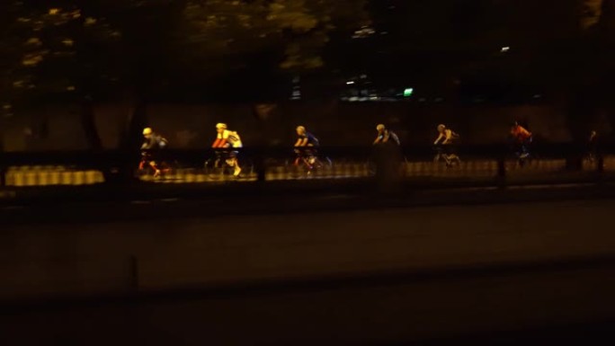 骑自行车的人在城市的中心街道上进行夜间比赛，