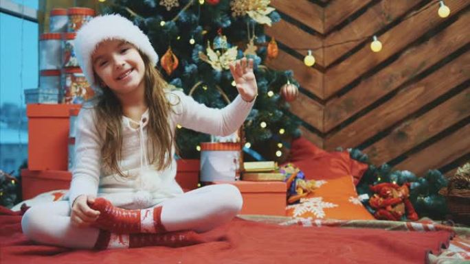 4k视频，年轻女性戴着圣诞帽挥舞着手，邀请所有人在木制背景上与她一起庆祝。
