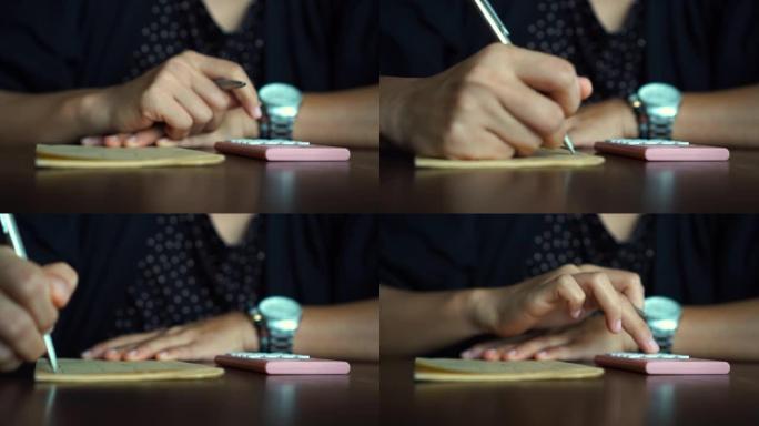 4k视频复制空间的人用手在白色笔记本上写下来，用计算器在咖啡馆背景下用bokeh灯计算。