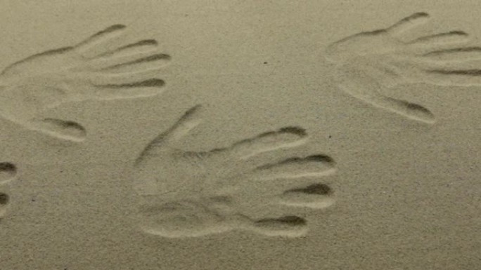 许多人类双手在沙滩上的印记，作为背景