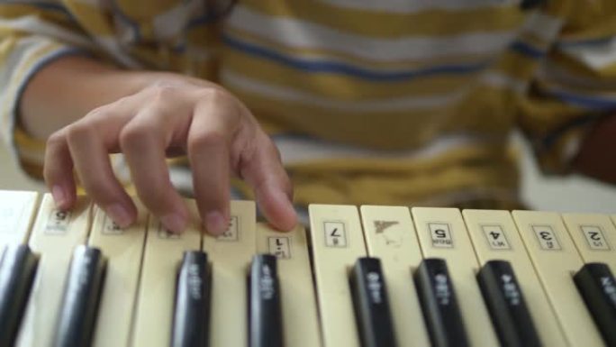 亚洲女孩在新型冠状病毒肺炎期间在家练习演奏键盘乐器的技巧。