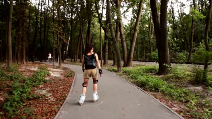 年轻快乐的女性在夏季公园享受轮滑。年轻迷人的女性正在公园里溜旱冰。