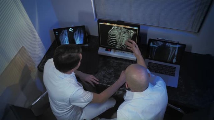 在控制室，医生和放射科医生在观看过程时讨论诊断。MRI或ct扫描程序。