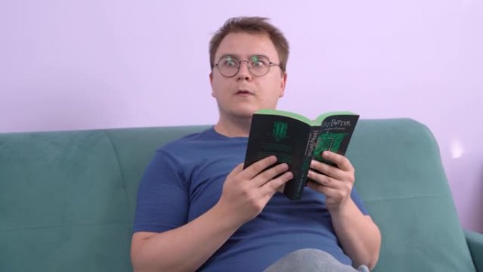 俄罗斯罗斯托夫2020年7月20日: 戴着眼镜的书呆子读了一本关于哈利·波特的平装书，有些东西引起了