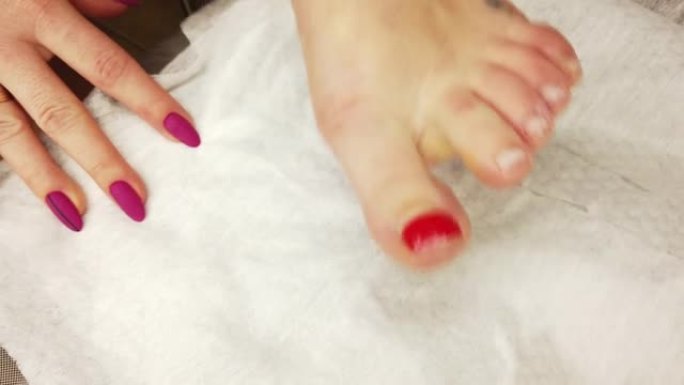 一个女孩在家做修脚，用特殊的砂光机，五金件修指甲擦亮脚趾甲。