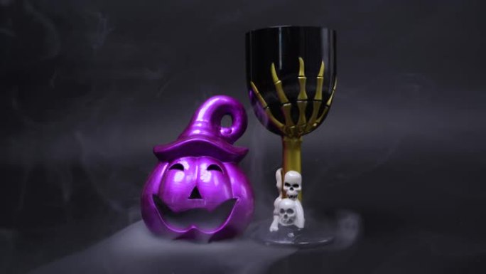 紫色杰克灯笼南瓜，带着险恶的微笑，带着头骨和骷髅手的令人毛骨悚然的高脚杯，用于装饰万圣节派对的房间，