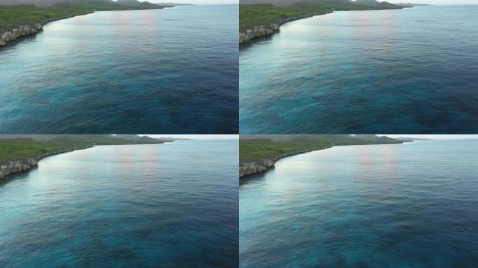 库拉索岛/加勒比海海岸的空中日出视图，有碧绿的水、悬崖和西蓬周围的游泳海豚