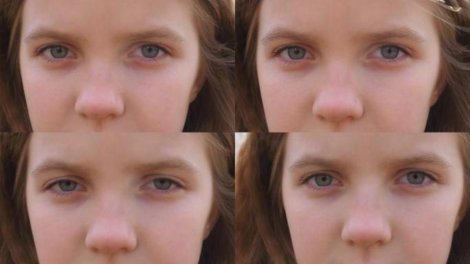 关闭不快乐的金发小女孩的蓝眼睛眨眨眼，看着镜头，带着绝望的景象。沮丧的小孩悲伤的凝视。令人失望的女性