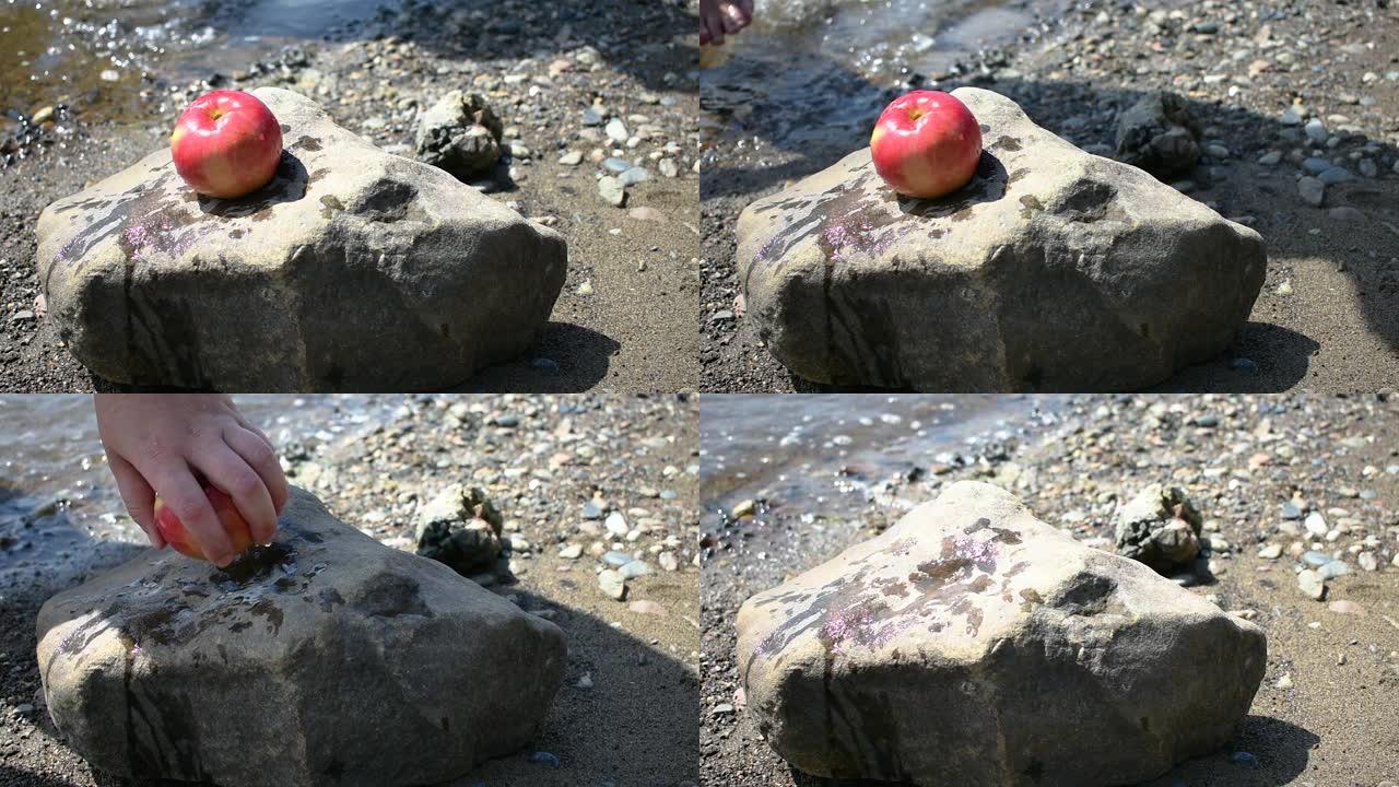男子从河边的石头上捡起一个苹果