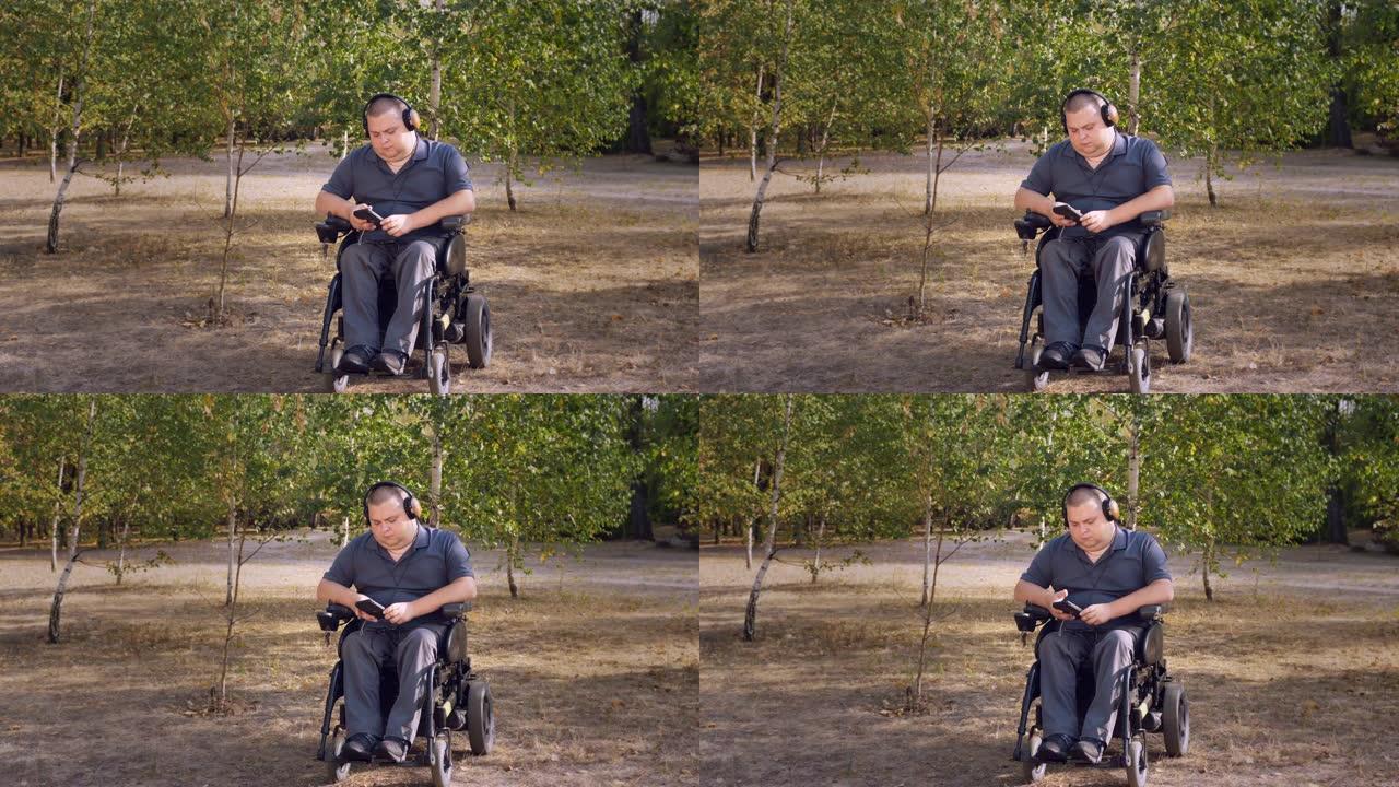轮椅男子。残疾人。年轻的残疾人，坐在自动轮椅上，在秋天的晴天，在城市公园里，戴着耳机听音乐