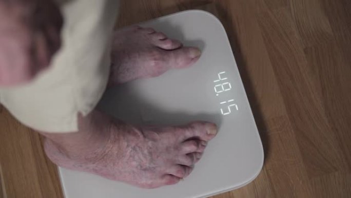 一位老年妇女的腿特写镜头上了电子地磅。一位脚趾酸痛，指甲可怕的高级女性在客厅的家庭秤上称重。健康退休