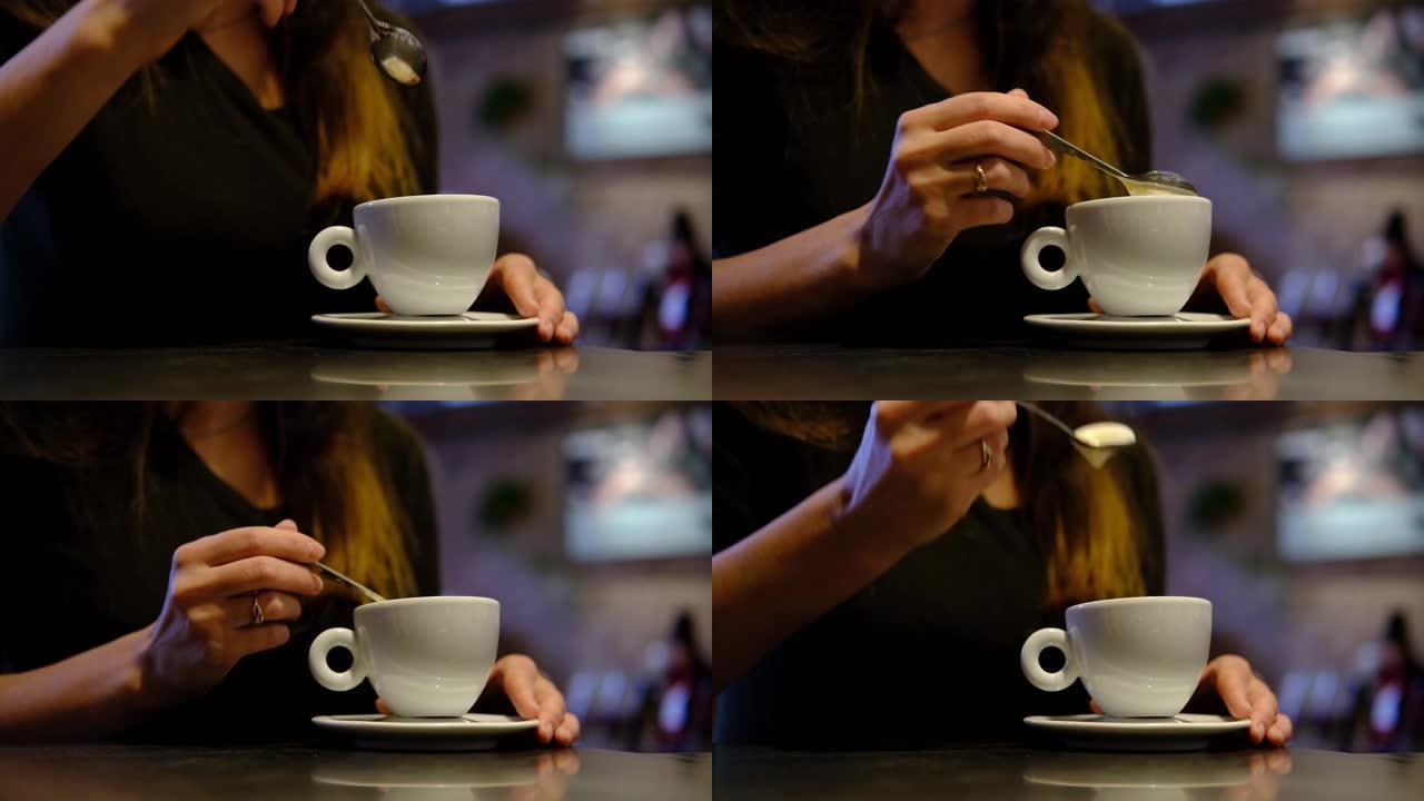 咖啡。在餐厅，咖啡厅用勺子喝咖啡的黑女人。特写女人用白色杯子双手。黑暗温暖的色调场景