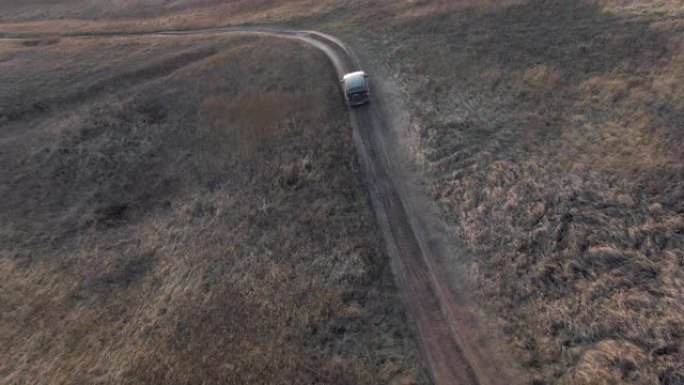 越野车黑色汽车行驶在乡村道路上鸟瞰图。越野车在土路上行驶，穿过村庄的乡村。