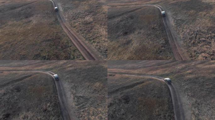 越野车黑色汽车行驶在乡村道路上鸟瞰图。越野车在土路上行驶，穿过村庄的乡村。