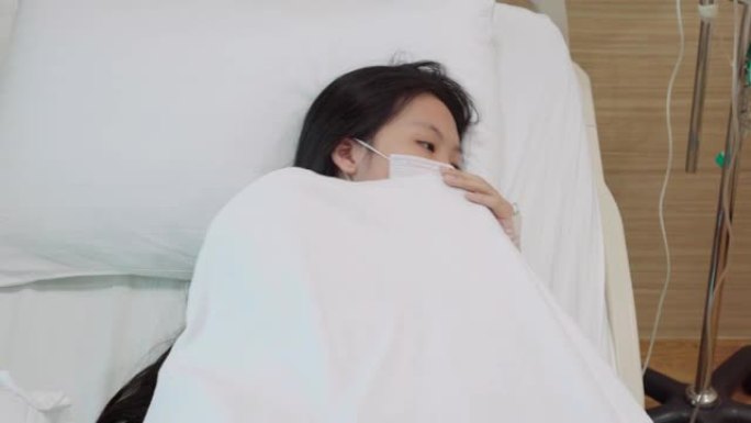 两张蒙面的亚洲少女在医院病床上咳嗽的镜头