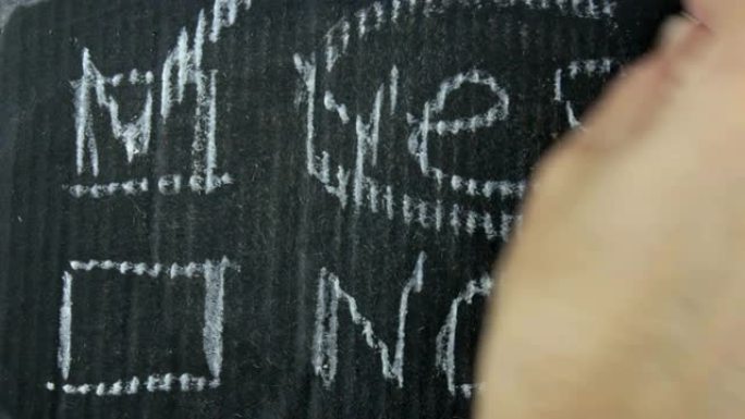 这个人在灰色的纸上用粉笔在选择栏中写下YES。一个男人的手的特写在灰色的纸上用粉笔写的YES的对面的