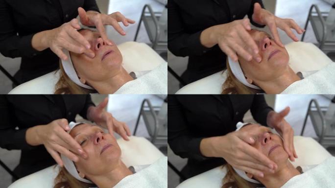 美丽快乐的白人妇女在水疗中心为客户做面部按摩-女性美容师医生美容师在沙龙应用面膜-保健概念
