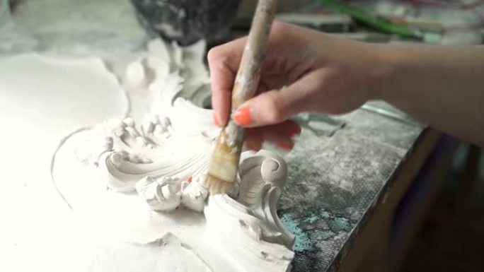 女雕塑家修剪整齐的手在白色石膏造型上