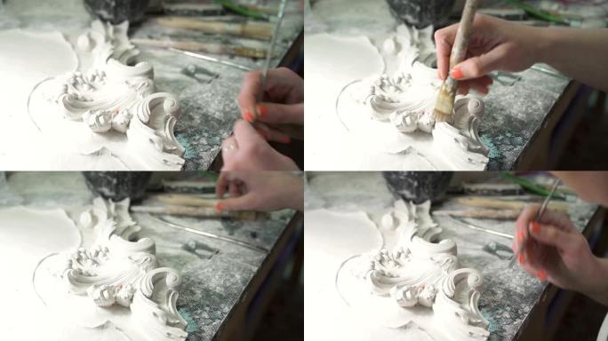 女雕塑家修剪整齐的手在白色石膏造型上