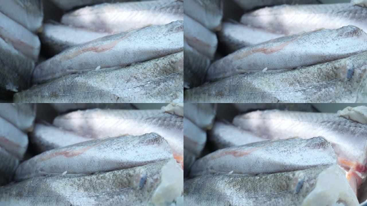 在白色铁板中解冻的新鲜冷冻灰色鱼