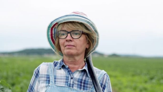 甜菜田上农夫的脸。女人用铲子走路。戴着眼镜和帽子的中年金发女郎。