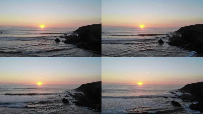 康沃尔南部海岸美丽的康沃尔日落。一个冲浪者享受着一天中最后几波涌向海岸的浪涛