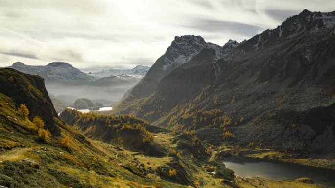 在意大利阿尔卑斯山乡村白山中，山峦丘陵和湖泊的秋天色彩鲜艳的冷杉树绿叶。夏天的山湖云时间流逝