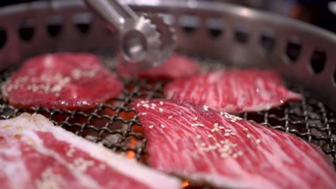 4k日式银色金属包拿起牛肉片放在烧烤架上，做得很好，中等稀有肉，煤火，日本餐厅，火焰烤，白盘，主菜