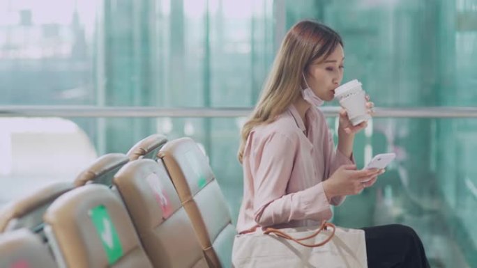 在机场用智能手机喝咖啡的年轻美女