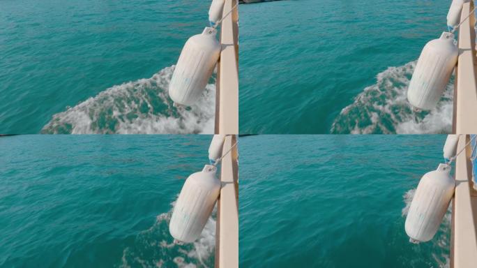 带有泡沫和波浪的侧浮船的尾水蓝色海面。海水背景上的白色浮标，有溢出物，气泡，帆船后的痕迹。