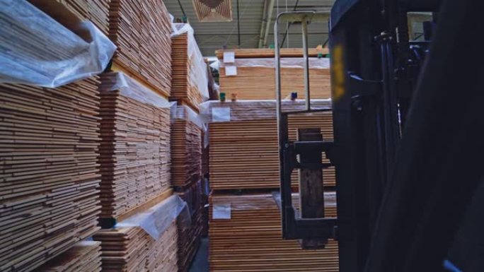 木工行业。叉车将一堆木板放在地板上。现代木材生产工厂。摄像机后退。